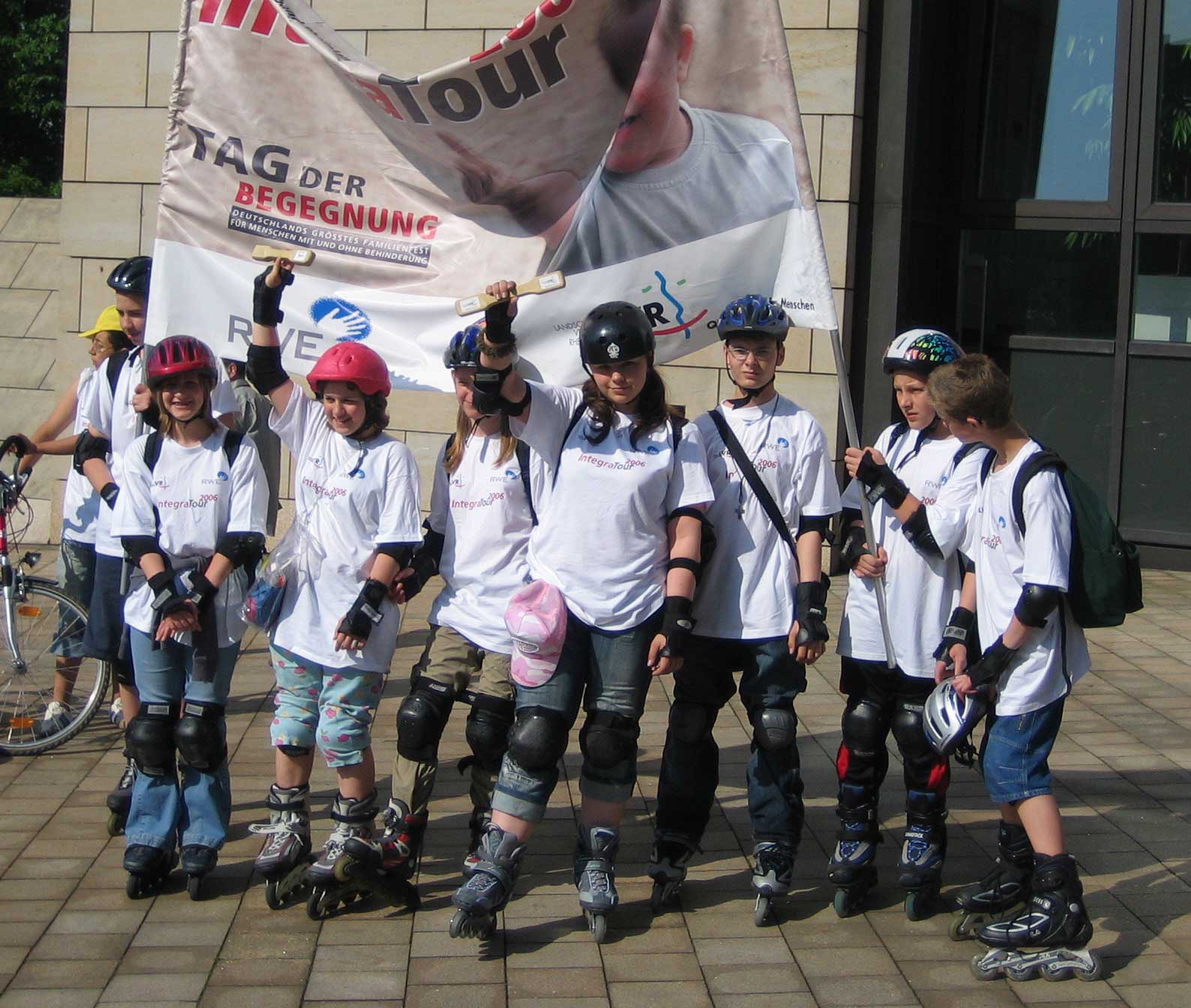 Eine Gruppe von Schlern auf Inline-Skates hlt Integra-Banner und Staffelhlzer in die Hhe.